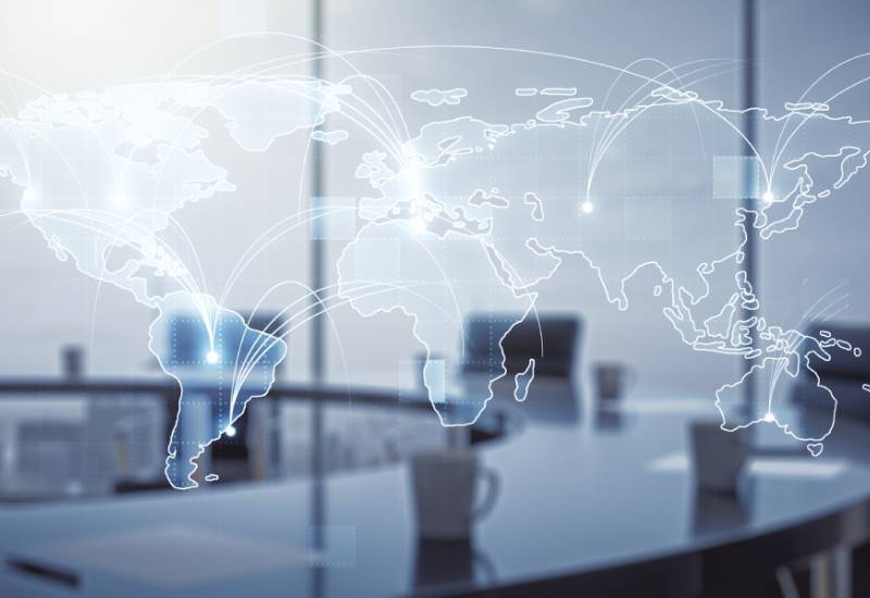World map overlaid on a boardroom table with connection lines to city markers symbolizing hubs