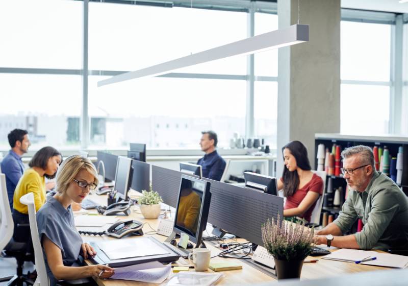 Diverse group of businesspeople sitting at their desk in an open office and working on their computers.