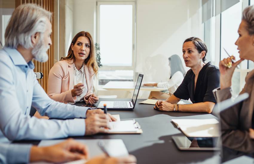 Business team huddles around a table and has a discussion in a meeting.