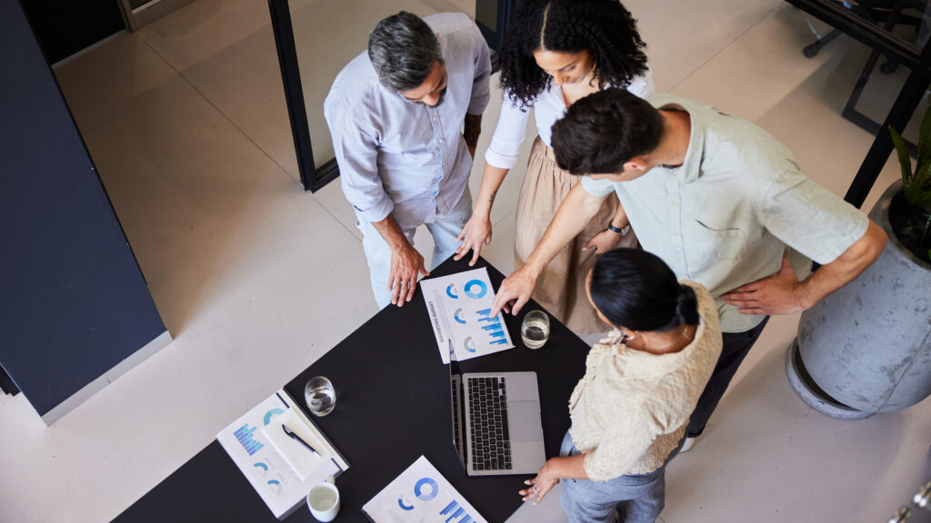 Top view of businesspeople meeting around a computer and data charts having a discussion