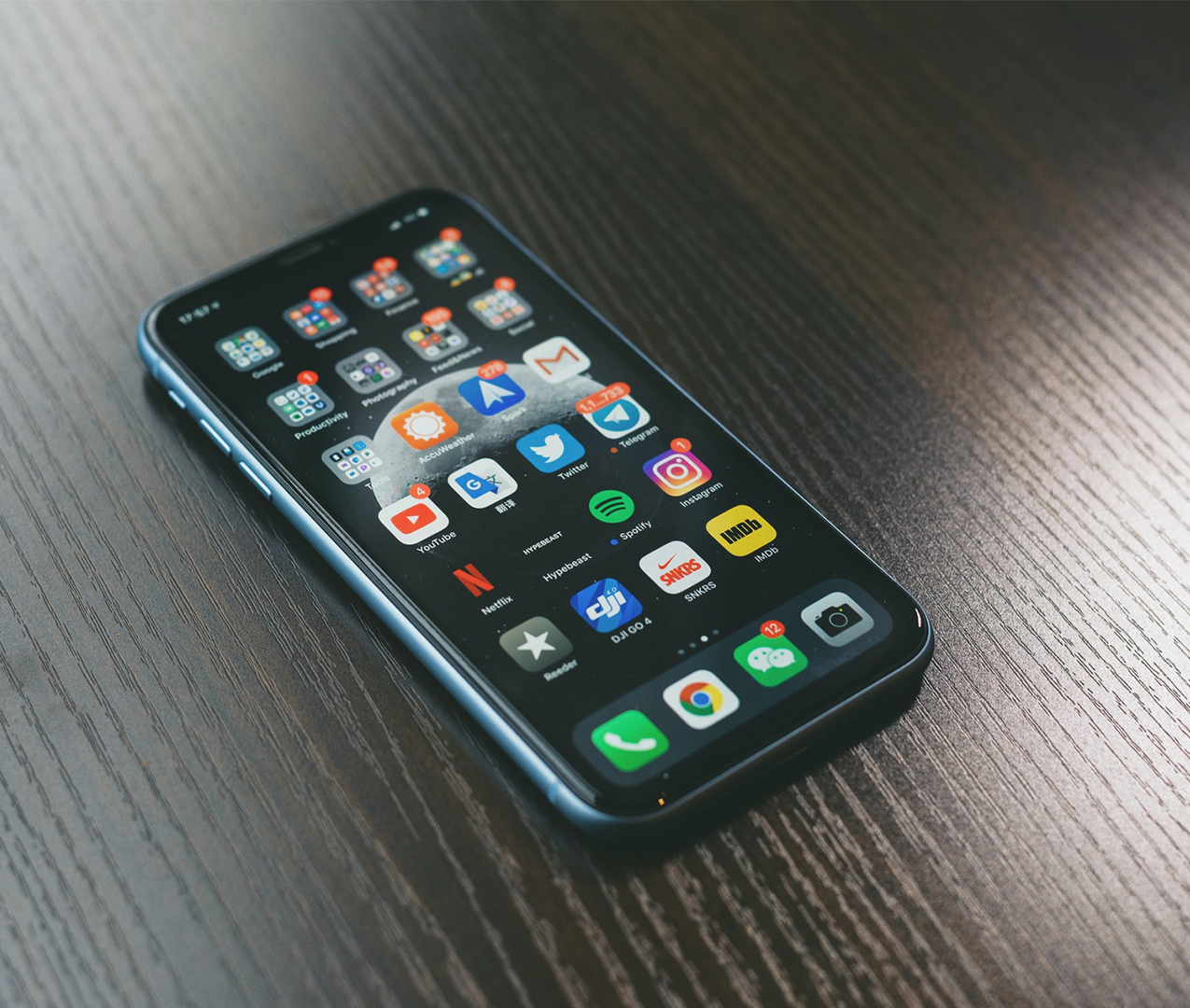 Unlocked Apple iPhone resting on table with apps home screen showing