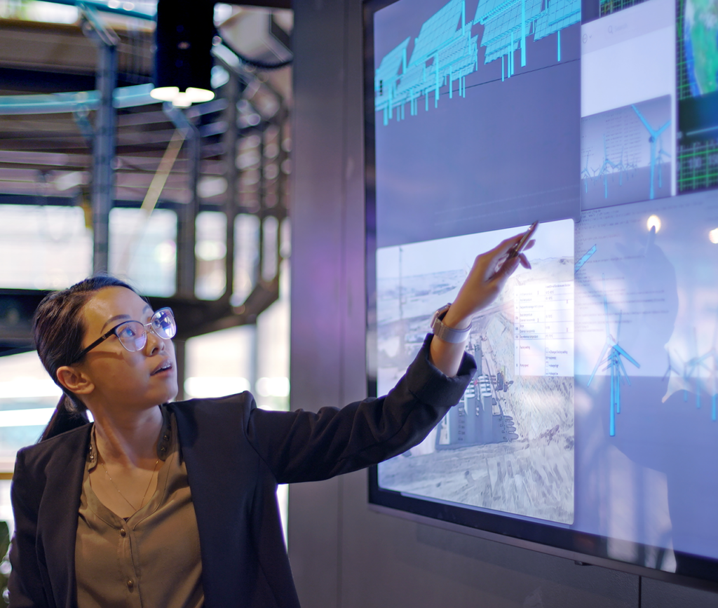 Lady pointing to data on large monitor