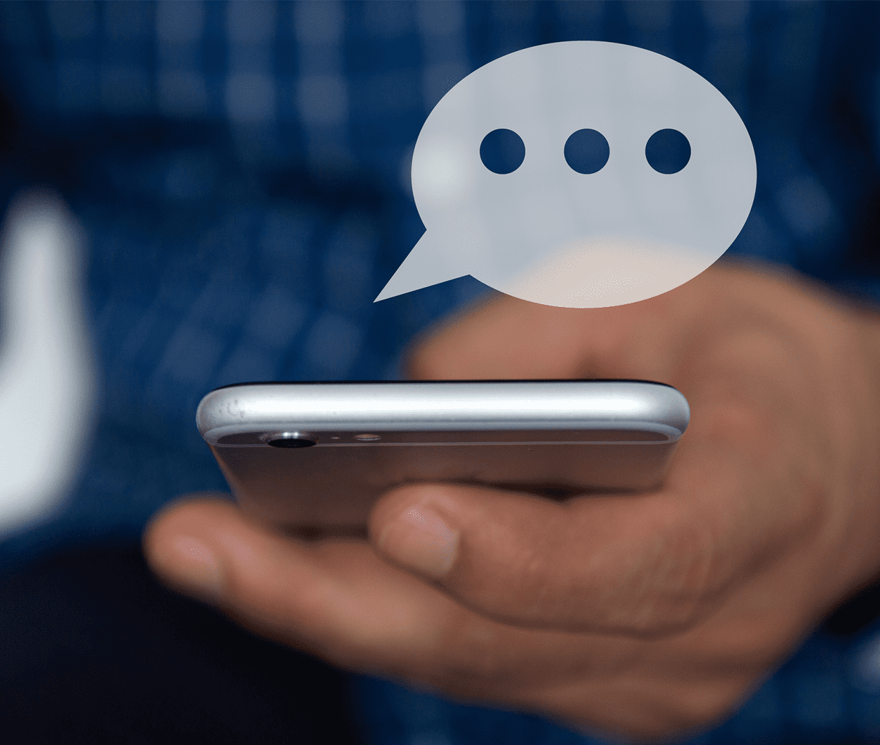 Close up of man holding cellphone with a chat bubble popping out of the screen.
