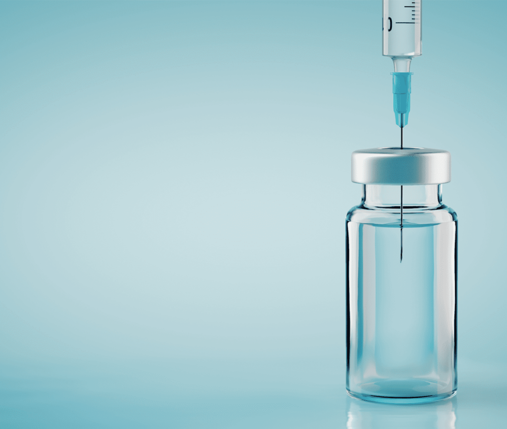 Syringe sticking in vaccine vial amongst a blue background.