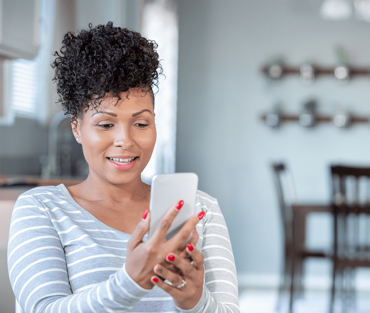 Middle-age woman holding up a mobile phone and talking to someone via video chat.