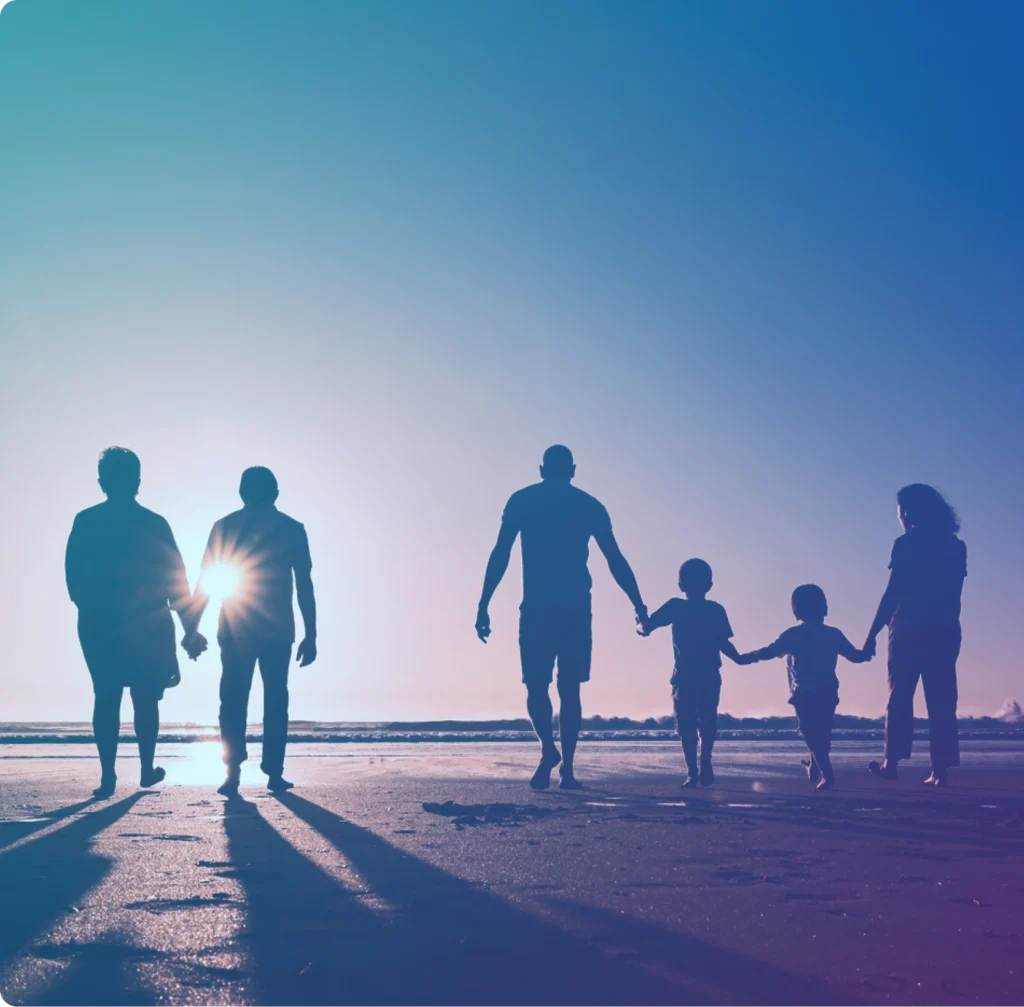 Silhouettes of a family of six walking hand-in-hand on a beach at sunset, with the sun low on the horizon.
